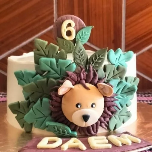Hand-sculpted fondant lion and leaf design on a birthday cake