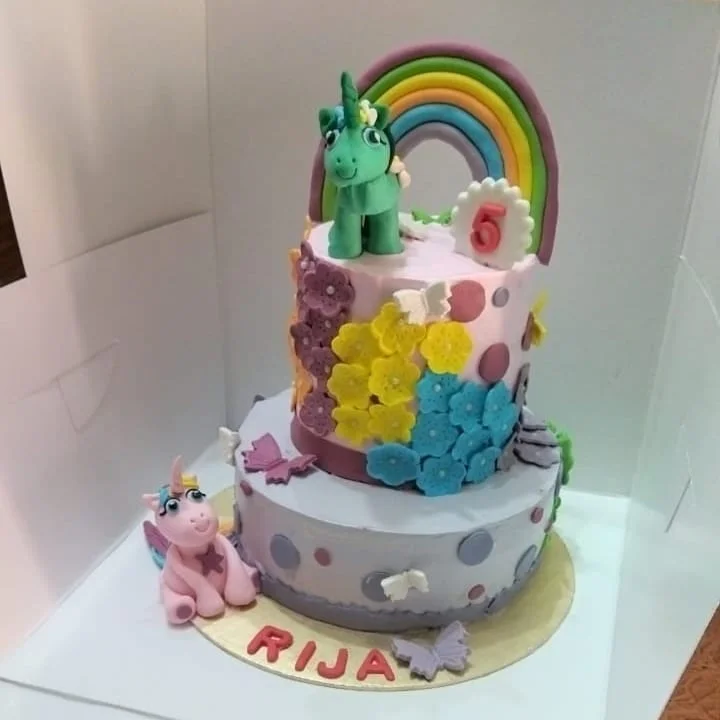 Two-tier cake with floral details and a unicorn topper